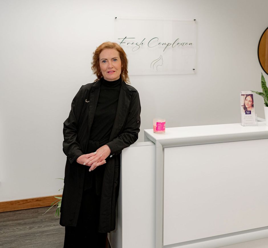 A woman in a black coat is standing next to a white counter.