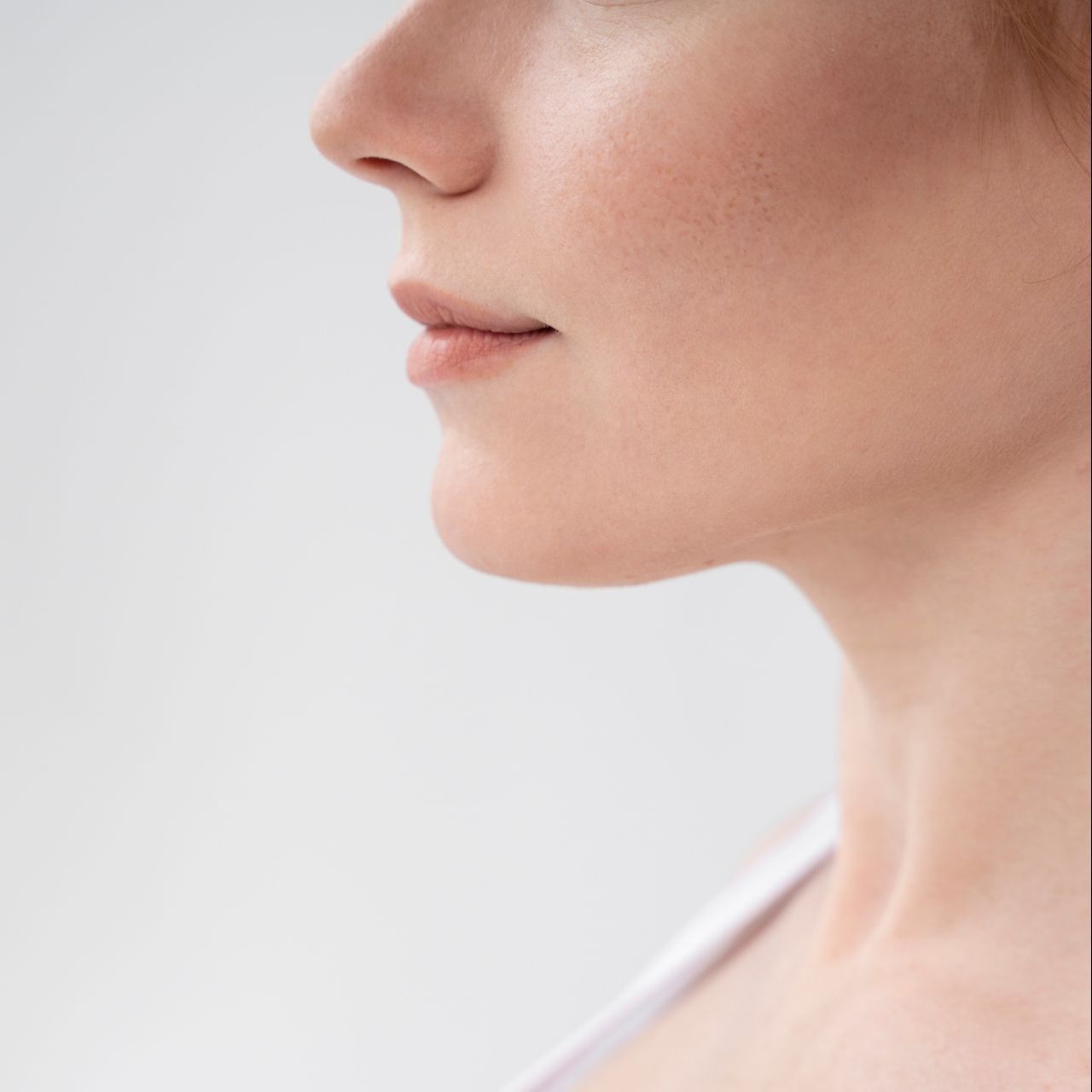 A close up of a woman 's neck and face against a white background.