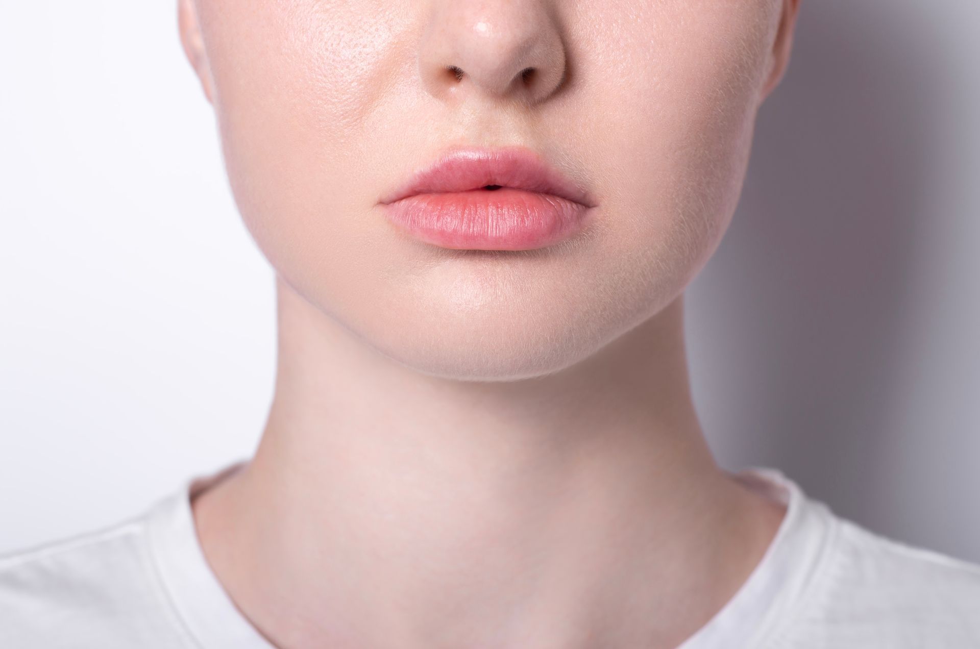 Close-up of a person's face. Focus is on the lips, nose, and part of the neck. The skin tone is pale.