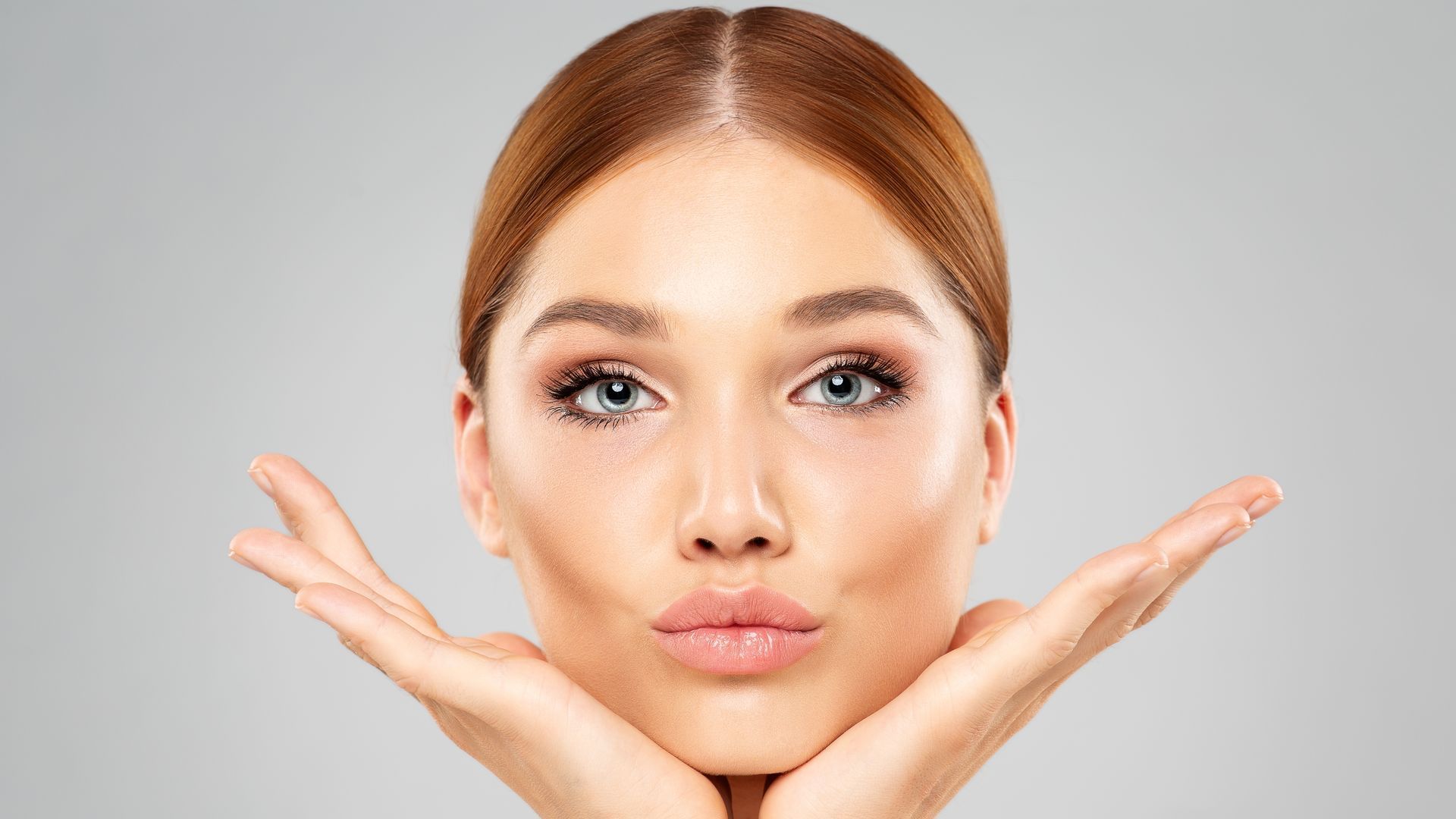 A woman is holding her face with her hands and making a funny face.