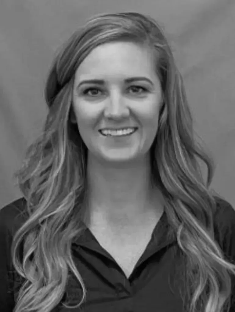 A woman with long hair is smiling in a black and white photo.