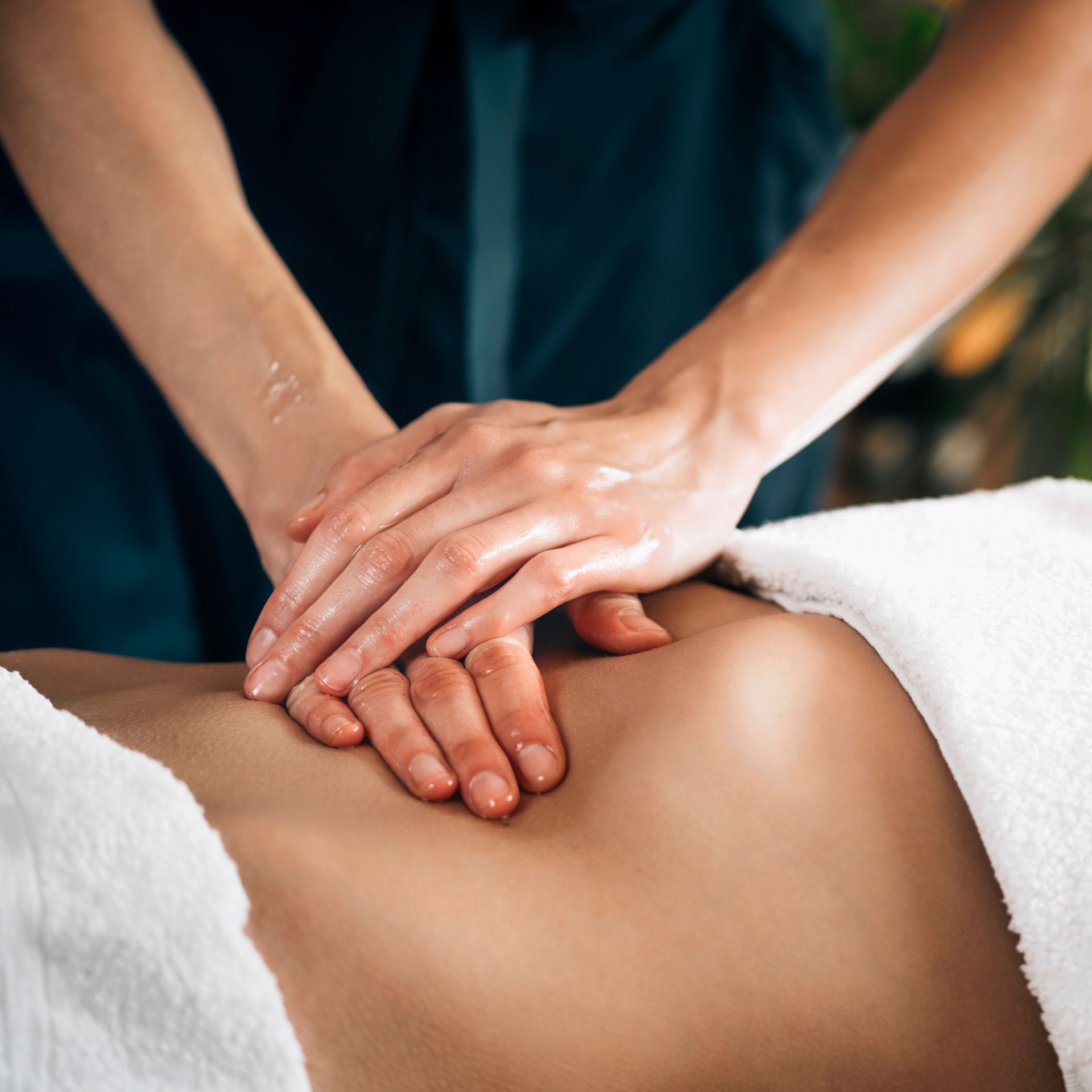 A woman is getting a massage with her hands on her stomach.