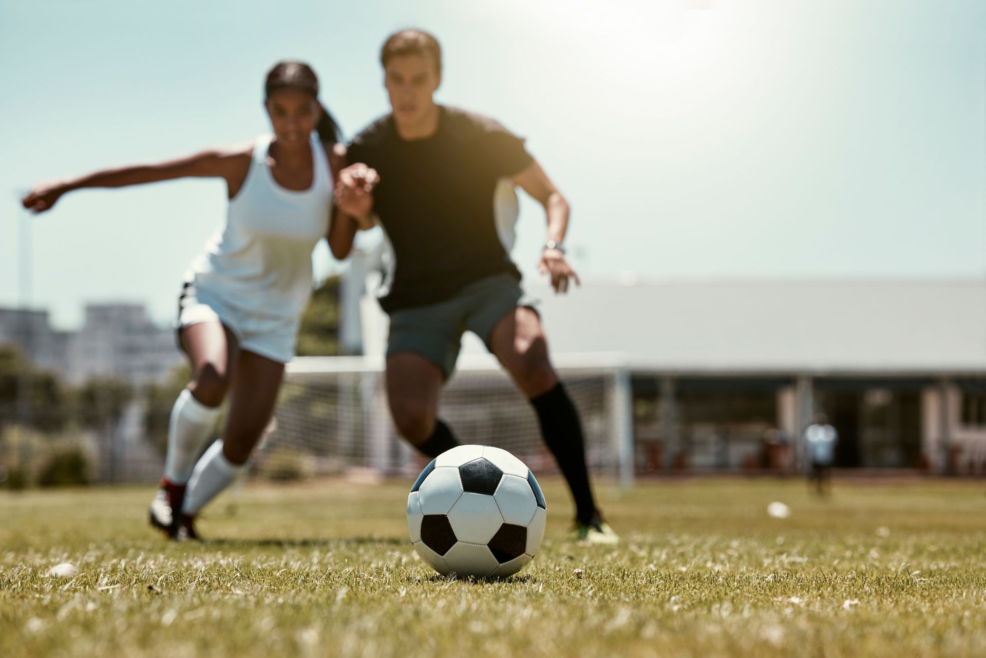 A man and a woman are playing soccer on a field.