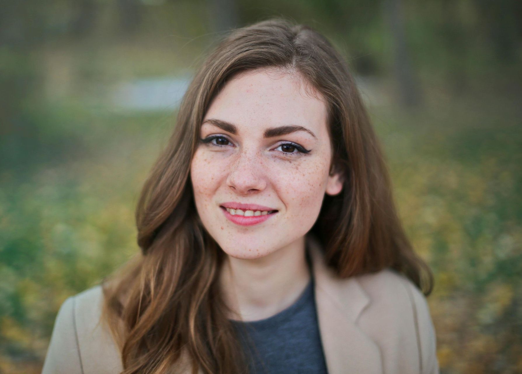 A woman with long hair and freckles is smiling for the camera.