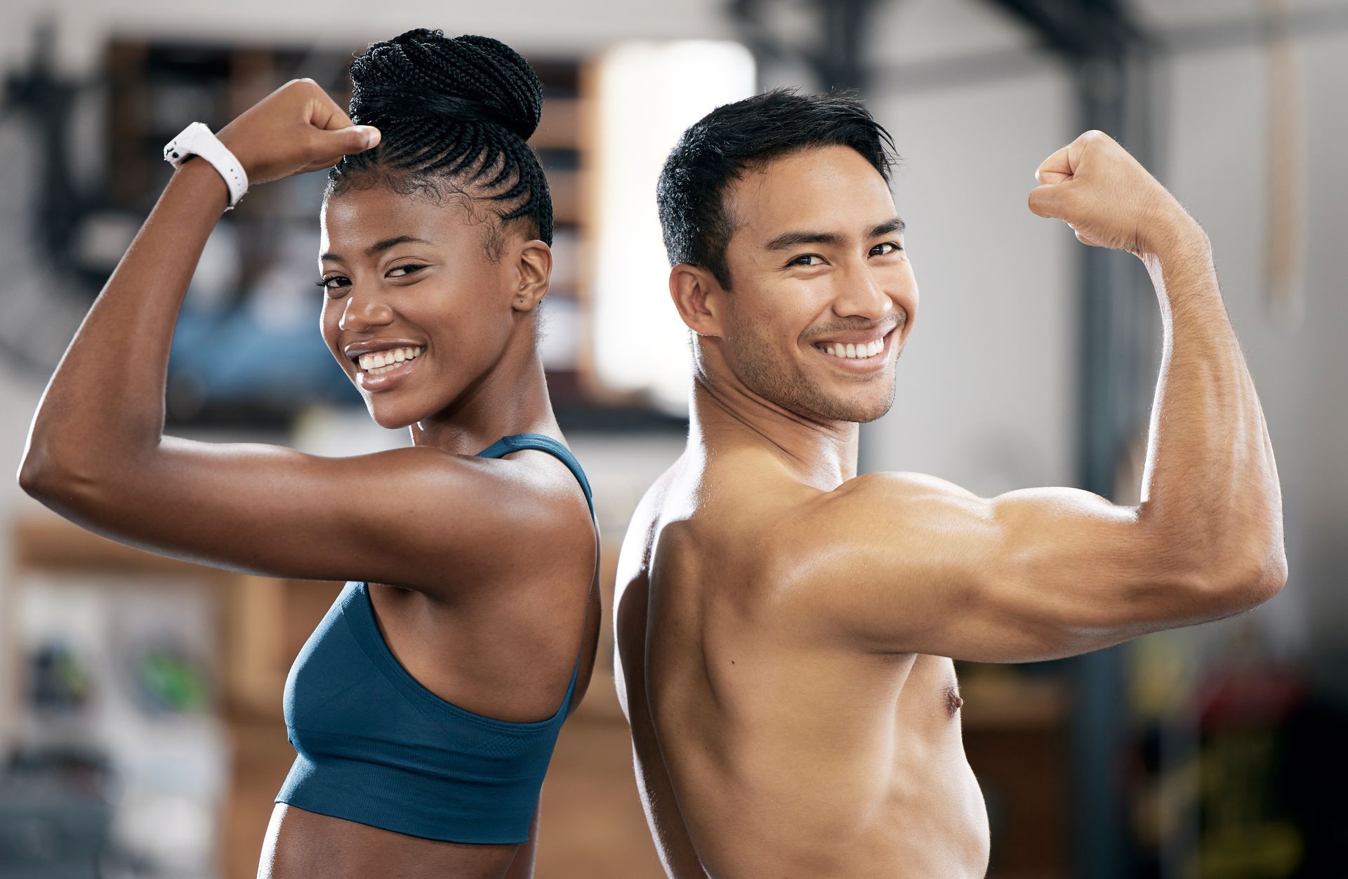 A man and a woman are flexing their muscles in a gym.