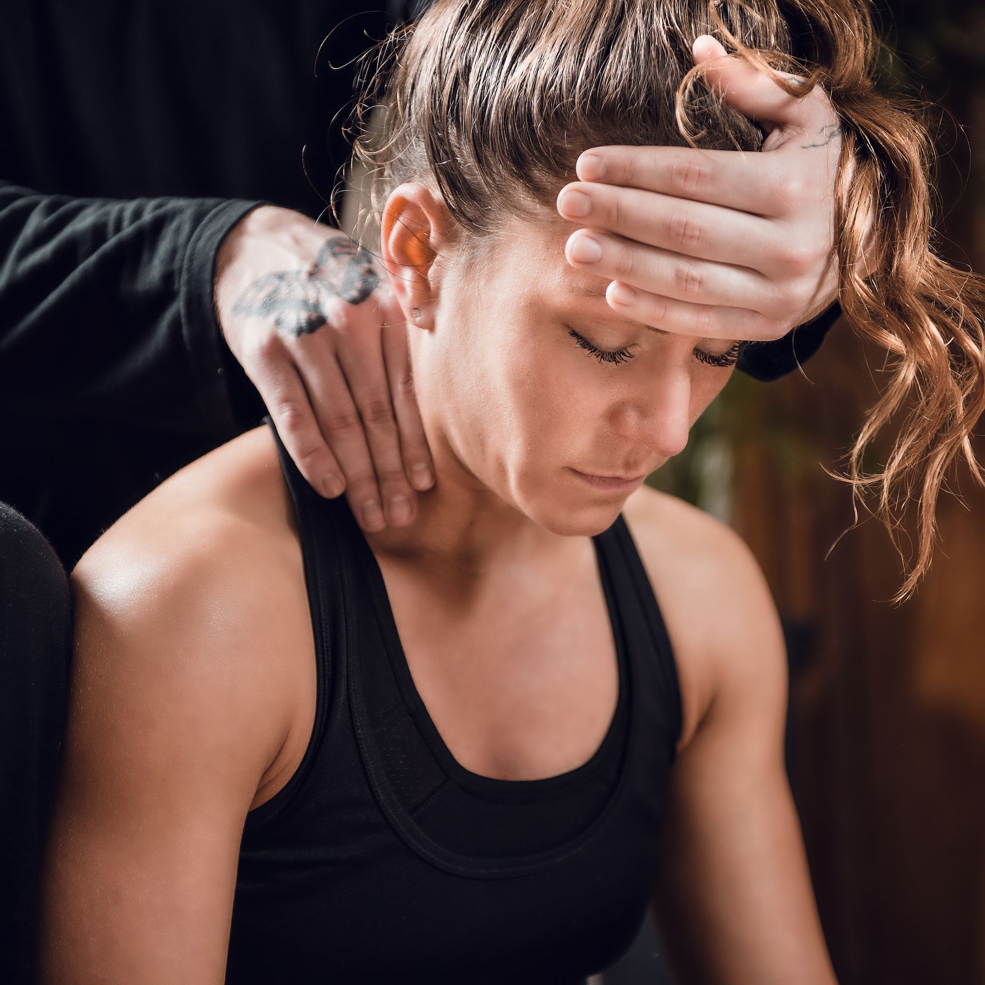 A woman in a black tank top is getting a massage from a man.