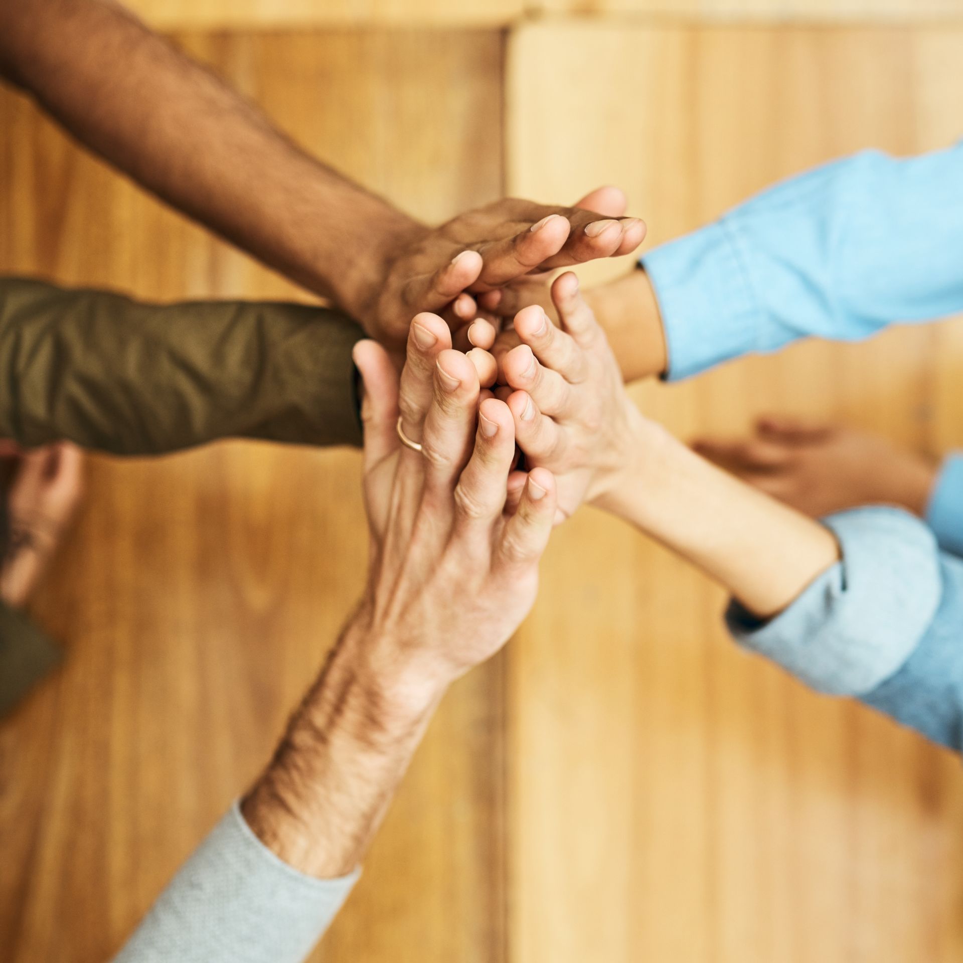 A group of people are putting their hands together.