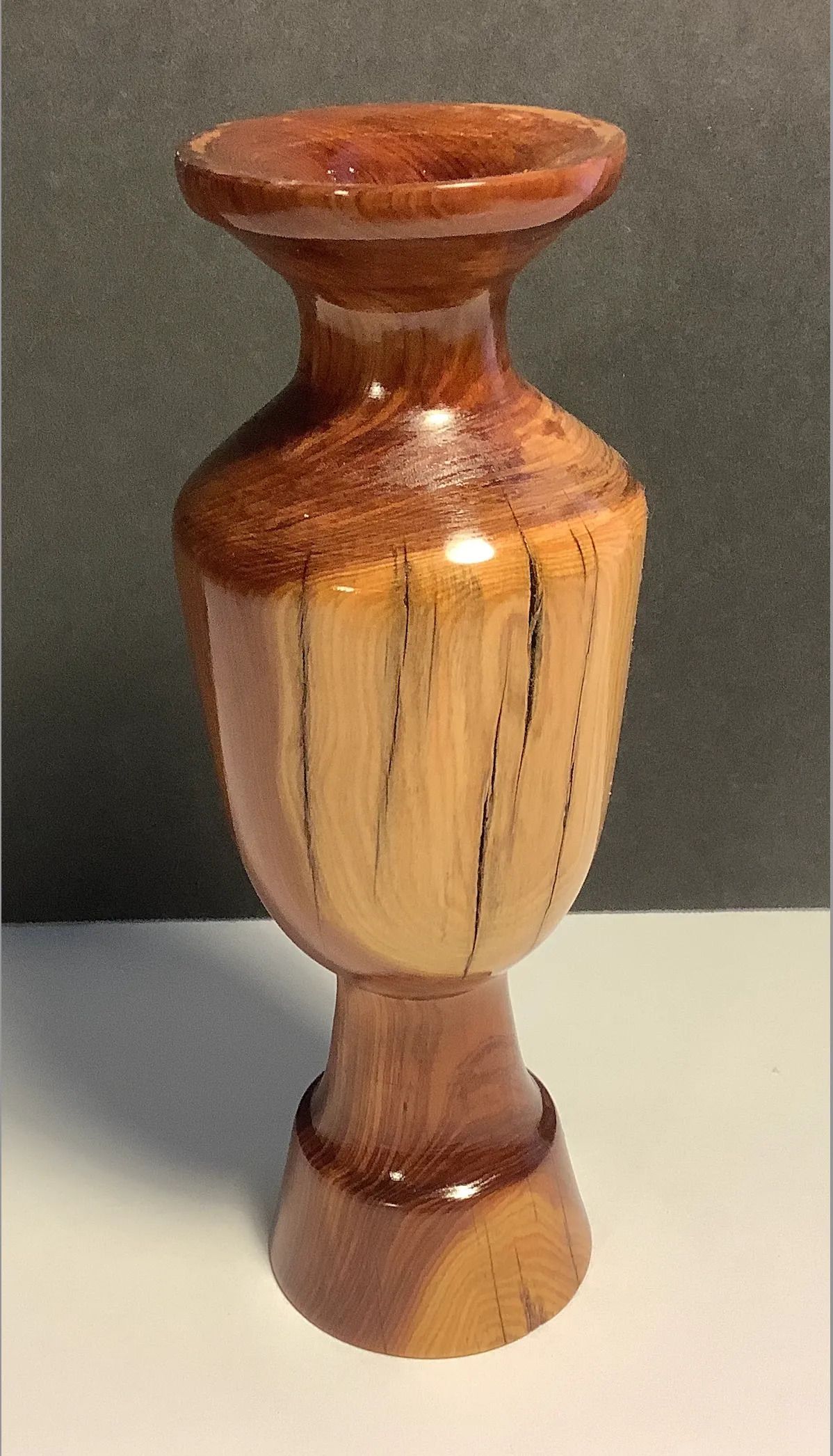 Wooden vase with a flared top, two-toned brown and beige, and a pedestal base.