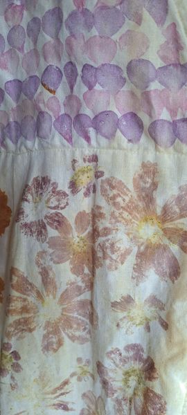 Fabric with floral and petal-shaped patterns in shades of purple and cream.
