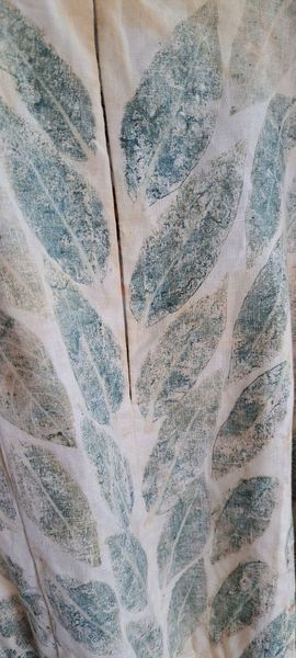 Fabric with blue-green leaf pattern. White and teal leaves against a white background with a vertical slit.