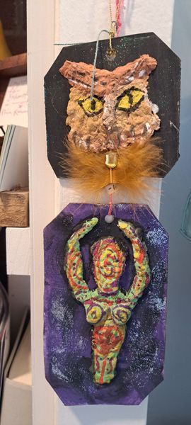 Two handmade art tags: cat face with yellow eyes, and a figure with arms raised against a purple background.