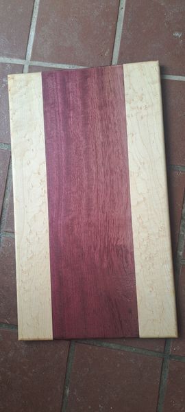 Wooden cutting board with a purple stripe down the middle, flanked by lighter wood.
