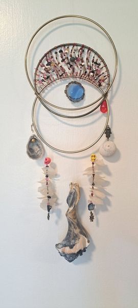 Dreamcatcher with stone accents and decorative elements hanging against a white wall.