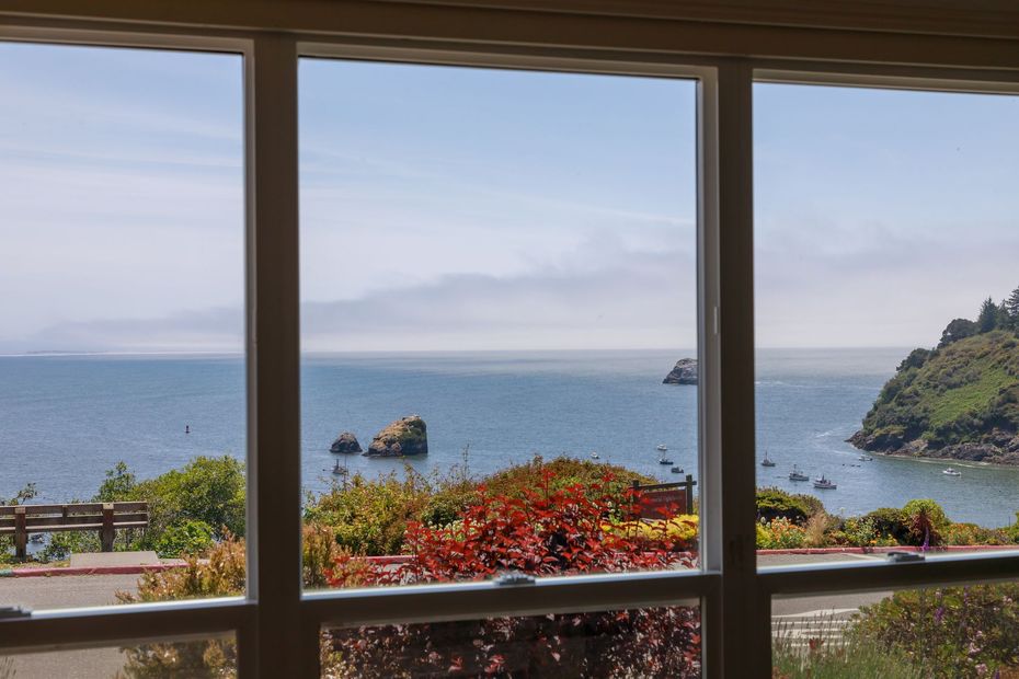 A view of the ocean through a window with a bench in the background