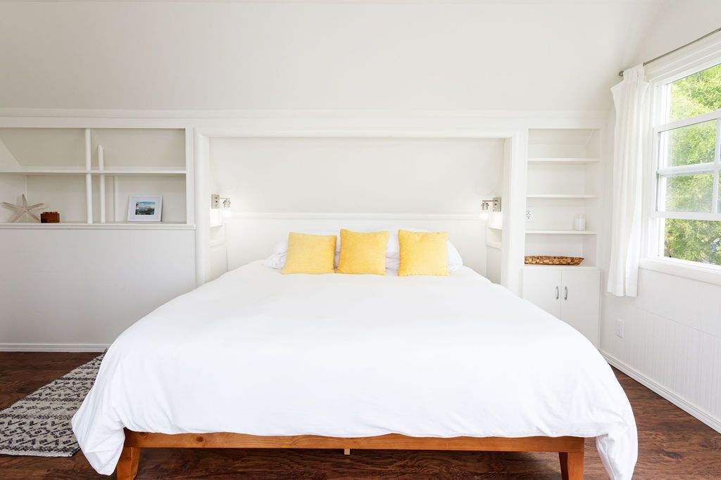 A bedroom with a king size bed and yellow pillows.