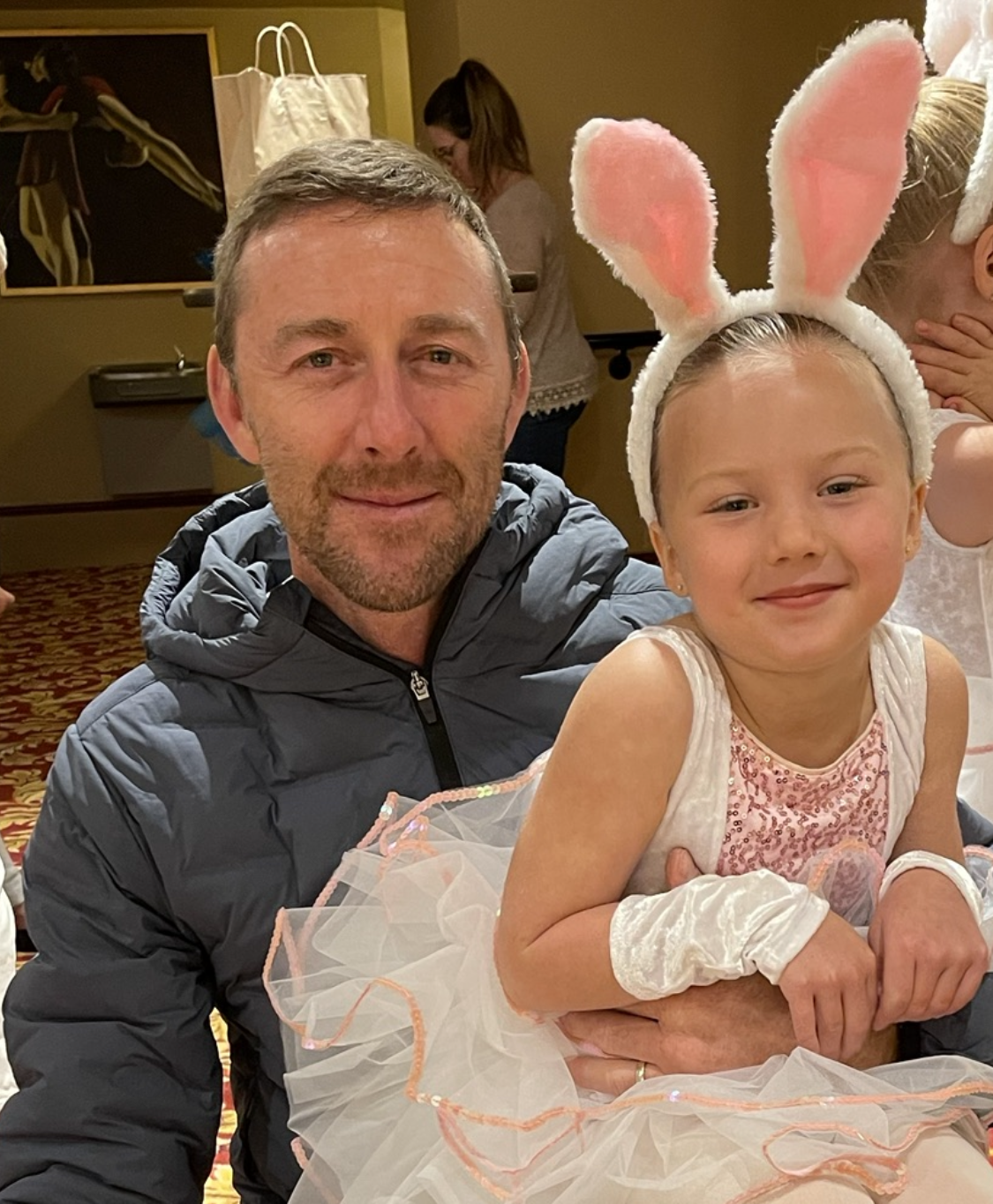 A man is holding a little girl in a bunny costume.
