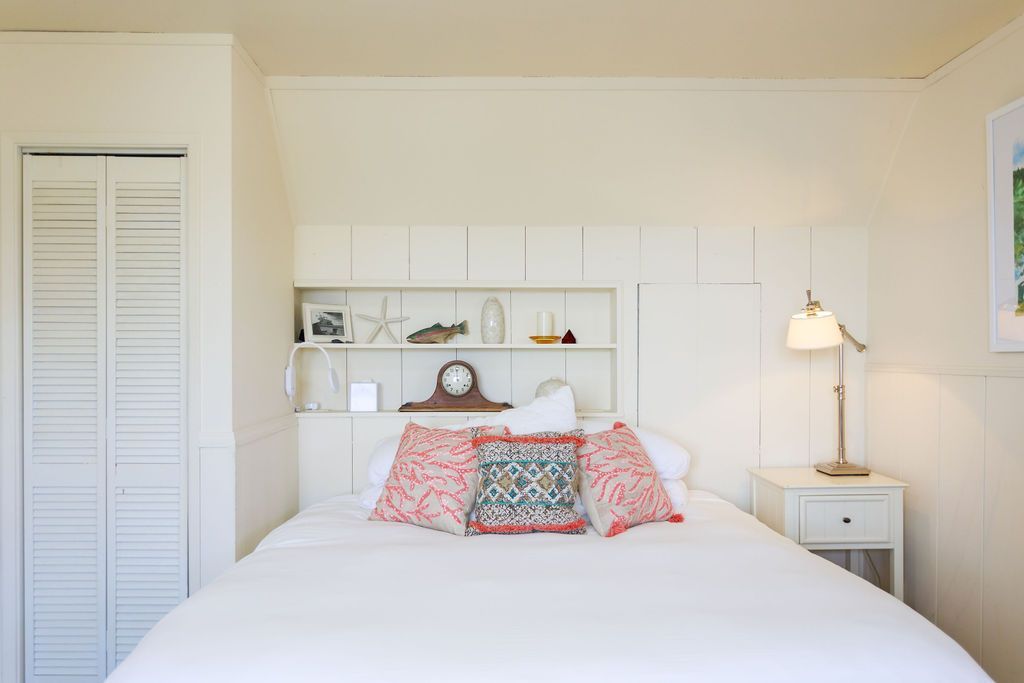 A bedroom with a bed , nightstand , lamp and closet.