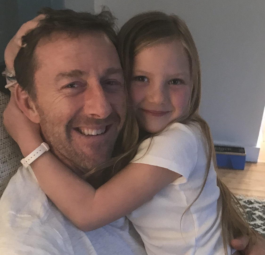 A man and a little girl are hugging and smiling for the camera