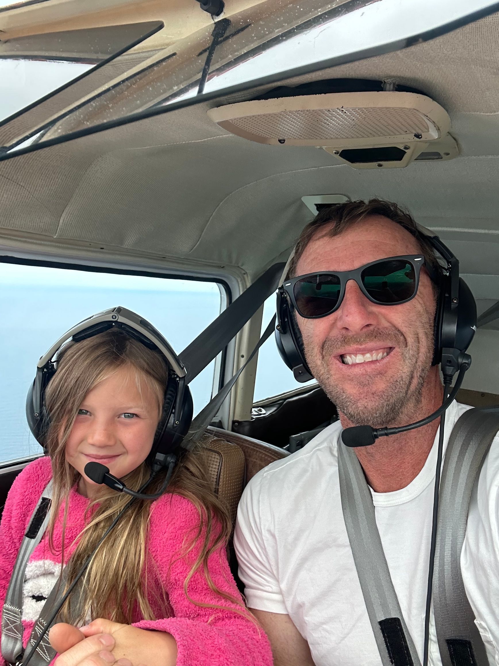 A man and a little girl are sitting in the cockpit of an airplane.