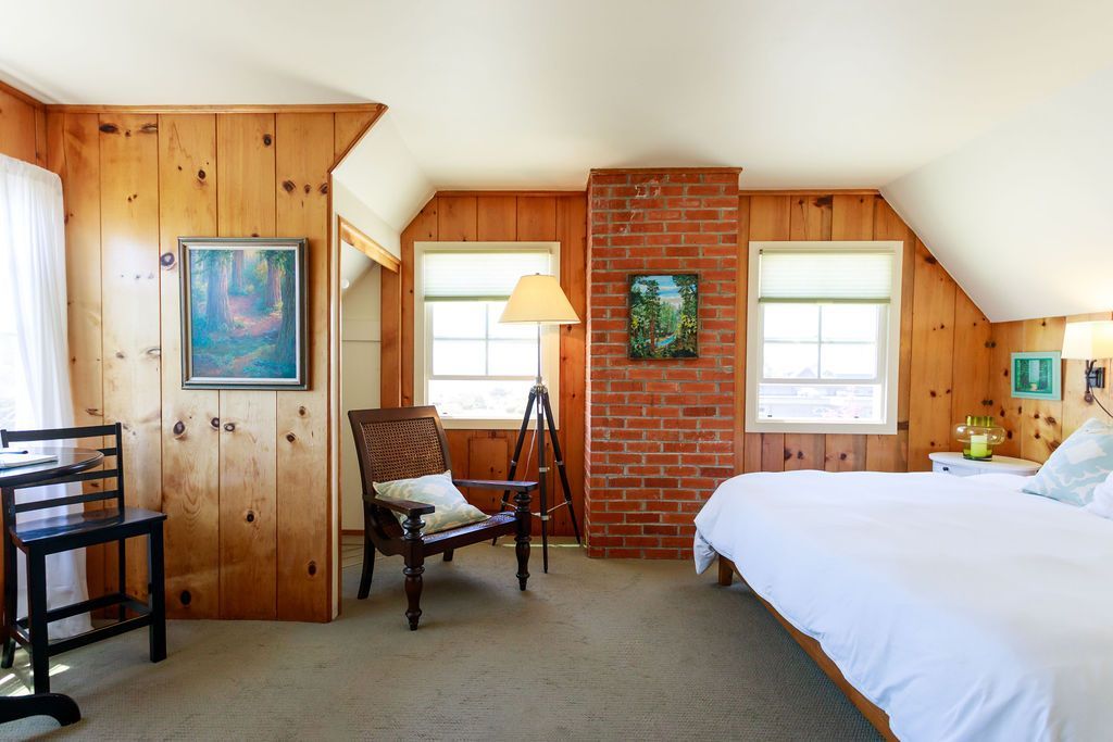 A bedroom with a bed a chair and a lamp