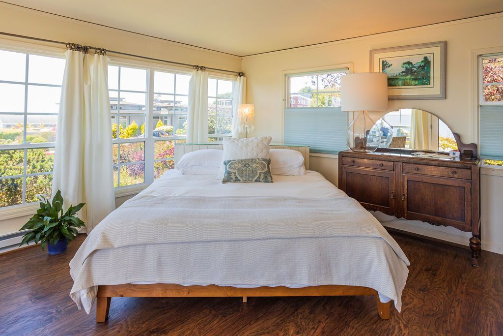 There is a large bed in the middle of the room with a lot of windows.