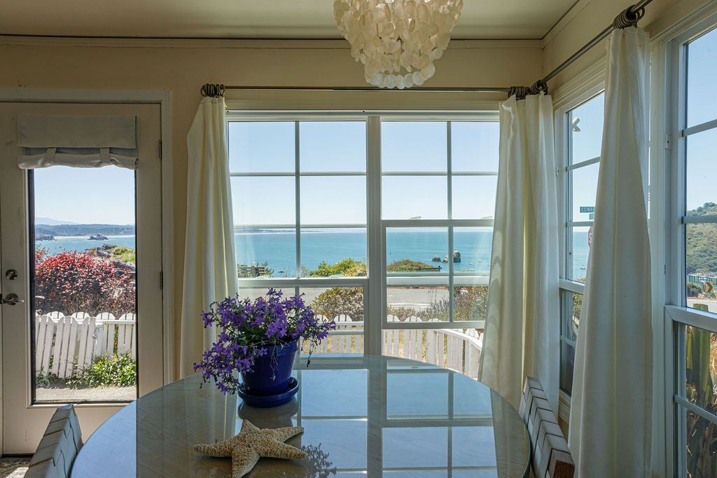 A dining room with a table and chairs and a view of the ocean.