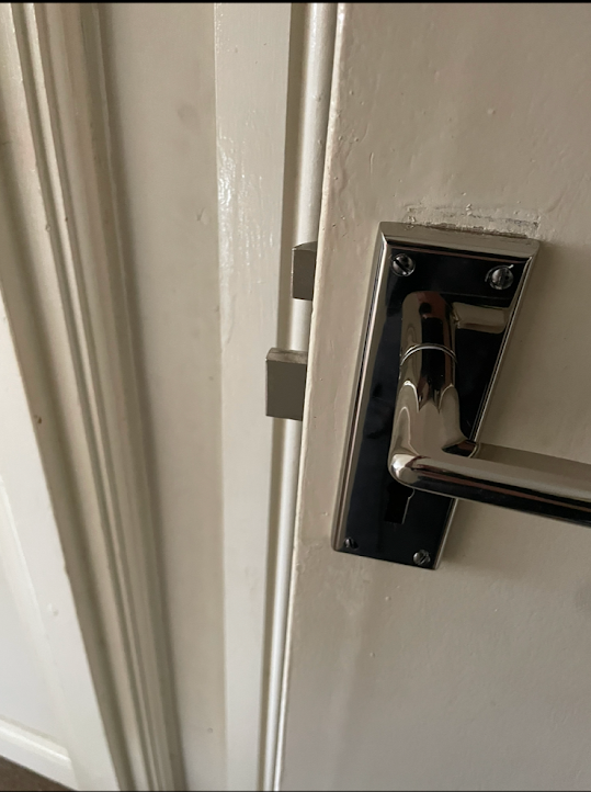 A close up of a door handle on a white door.