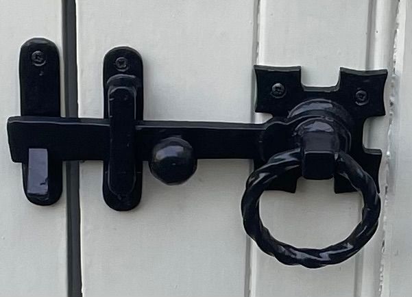 A close up of a black latch on a white door.