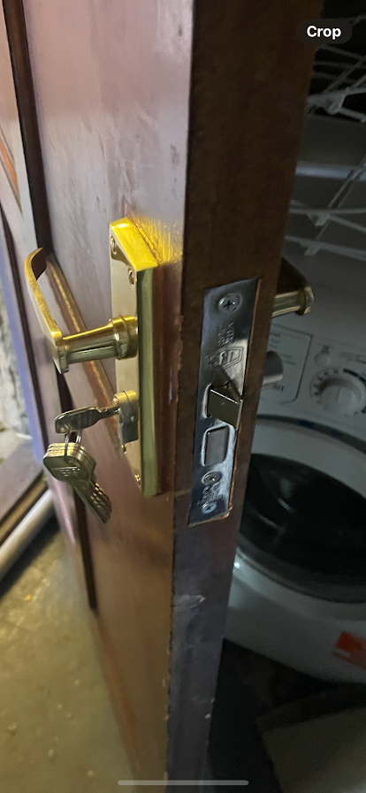 A close up of a door with a washer and dryer in the background.