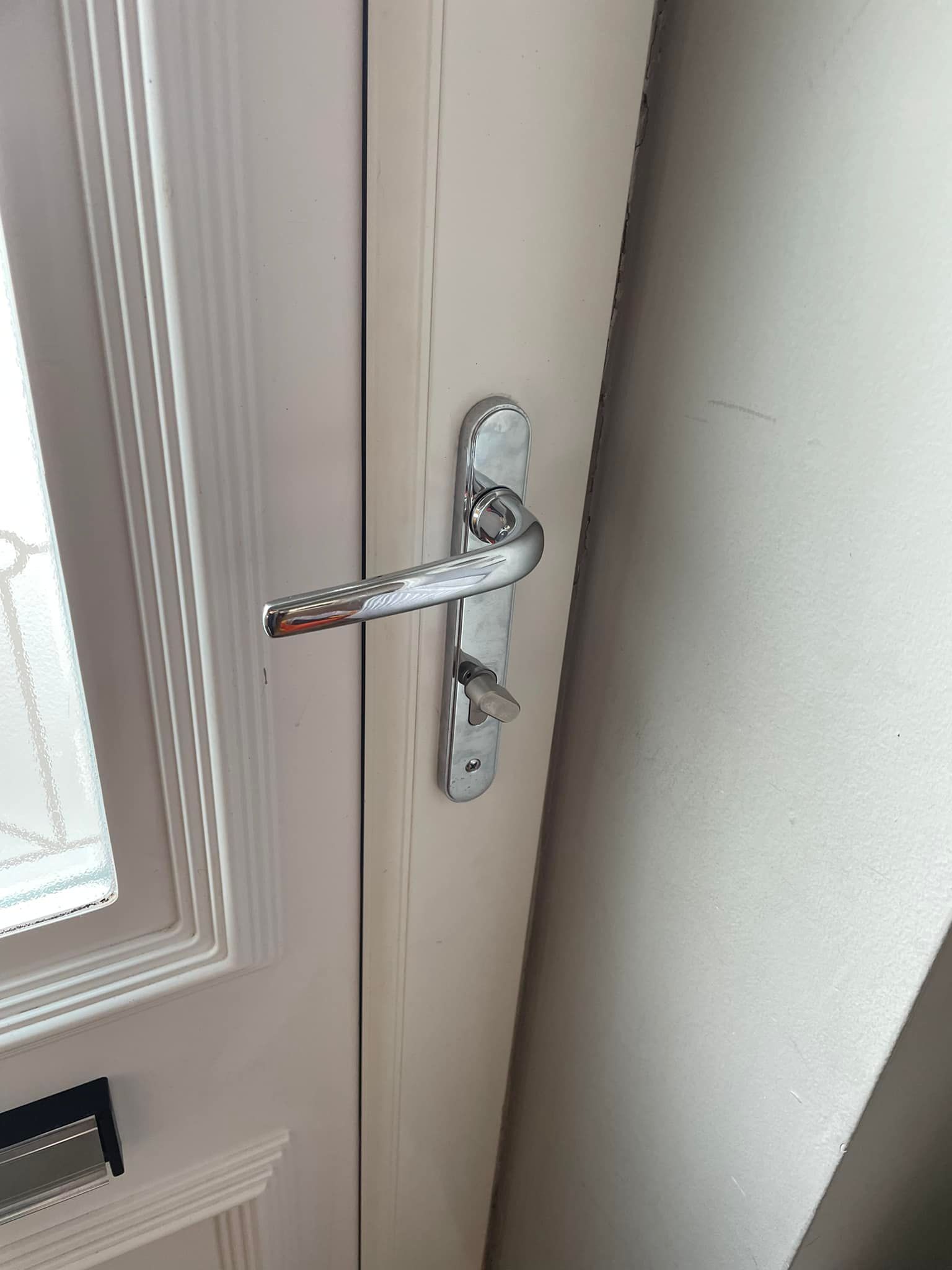 A close up of a door handle on a white door.
