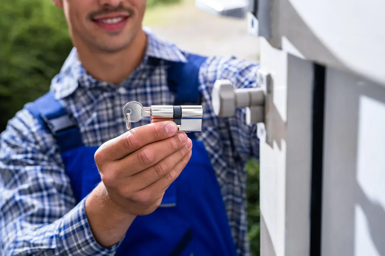 Technician adjusting a metal valve on white industrial equipment while holding a wrench