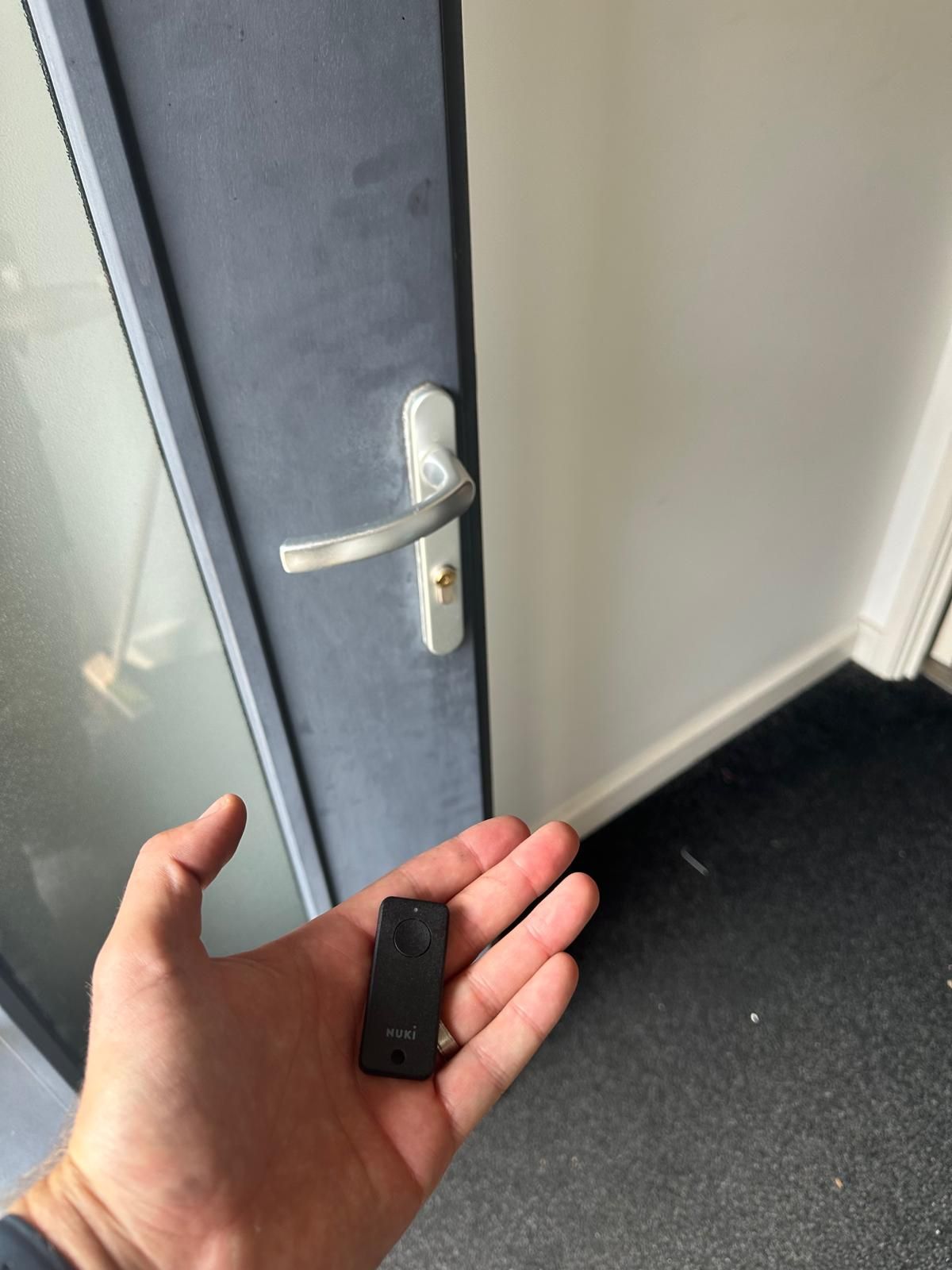 A person is holding a small object in front of a door