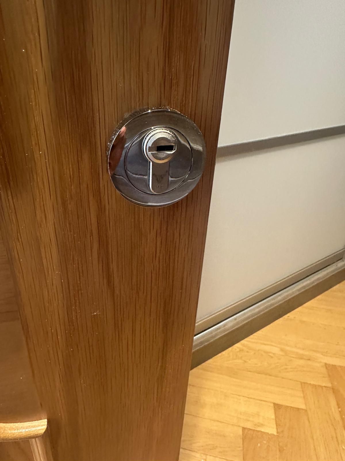 A close up of a door lock on a wooden door.