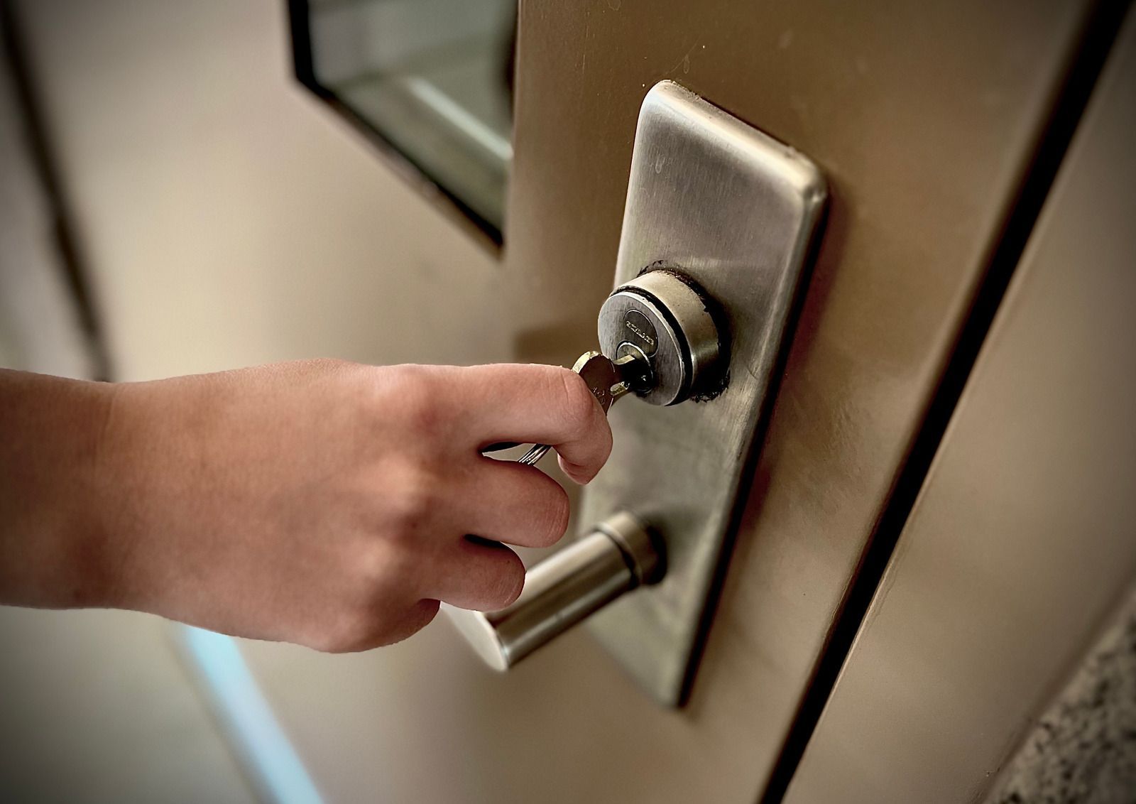 Person using a screwdriver to repair a doorknob on a wooden door.