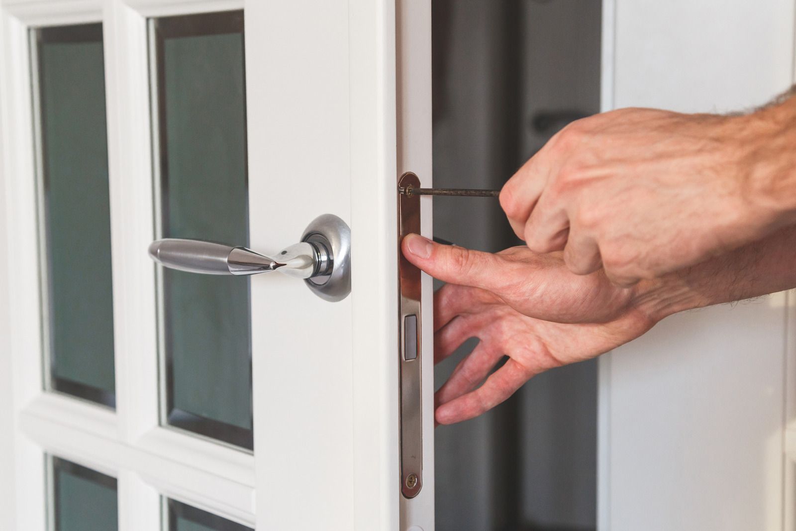 A person is fixing a door with a screwdriver.