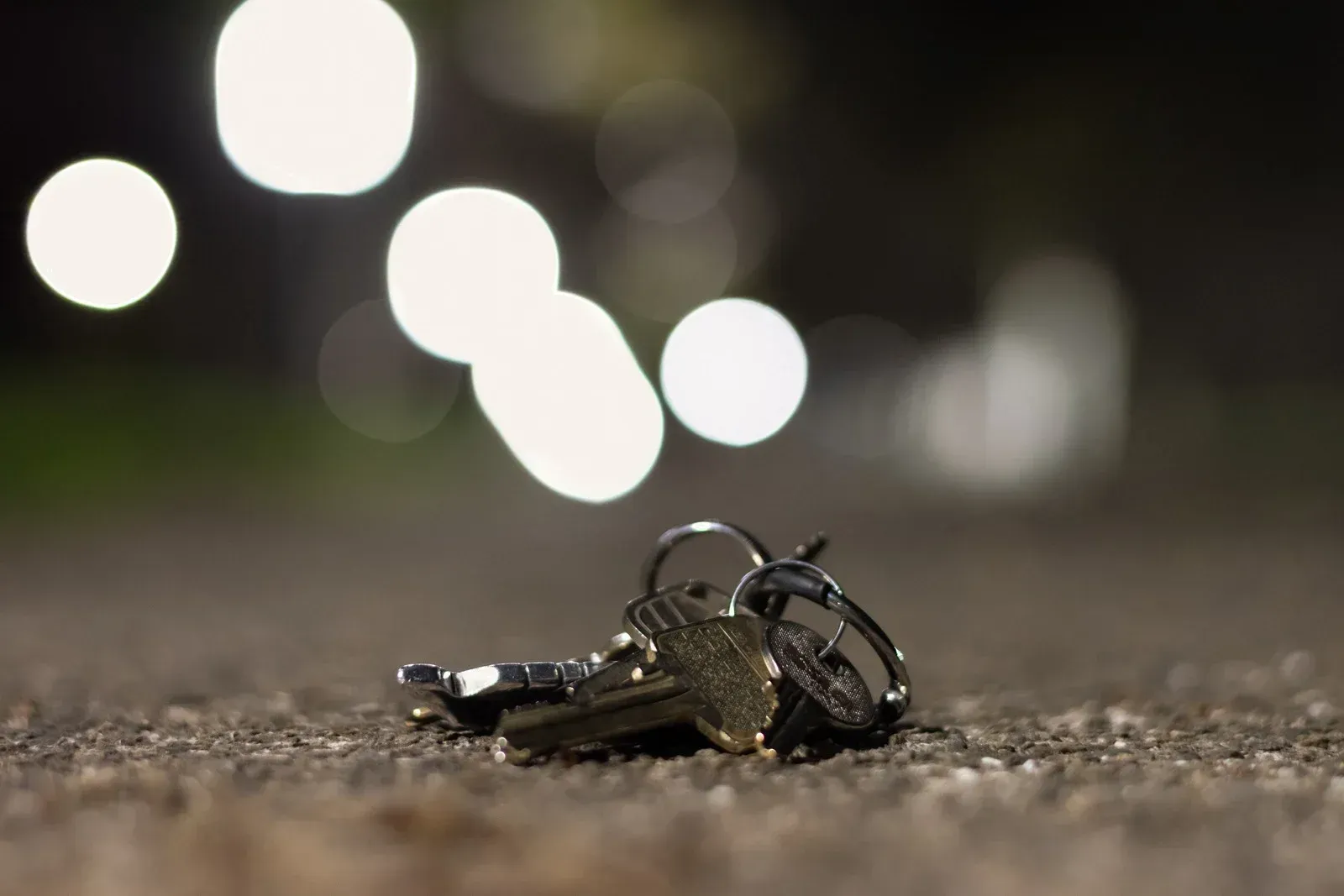 Keys on the ground at night; blurry streetlights in the background.