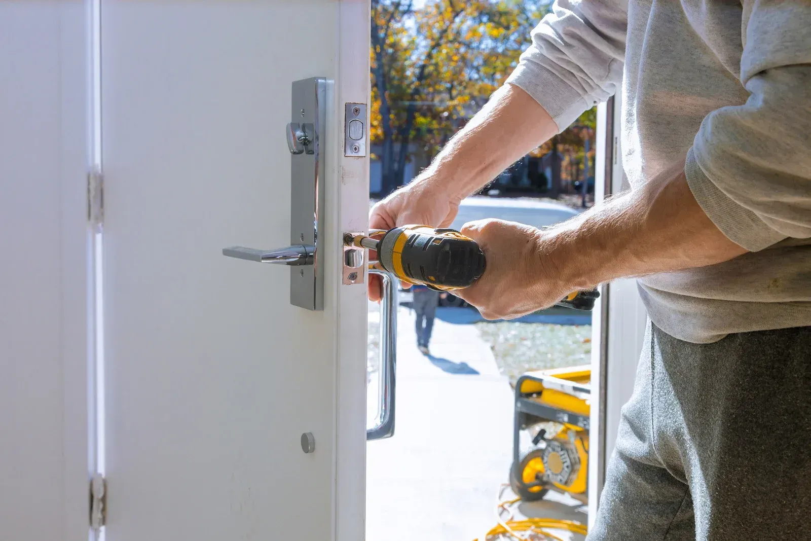 Person installing door lock with a power drill on a white door.