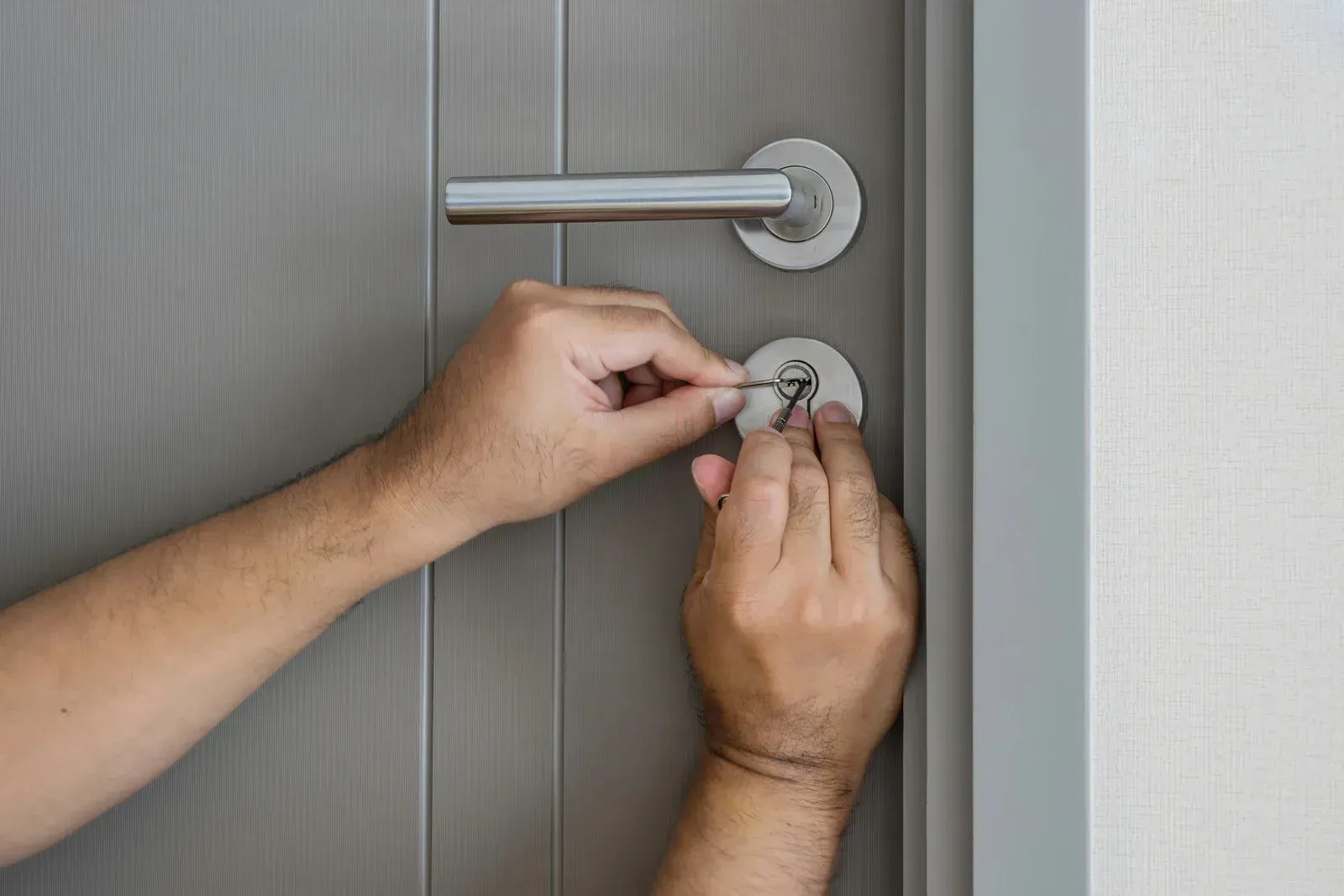 A person is using a screwdriver to open a door lock.