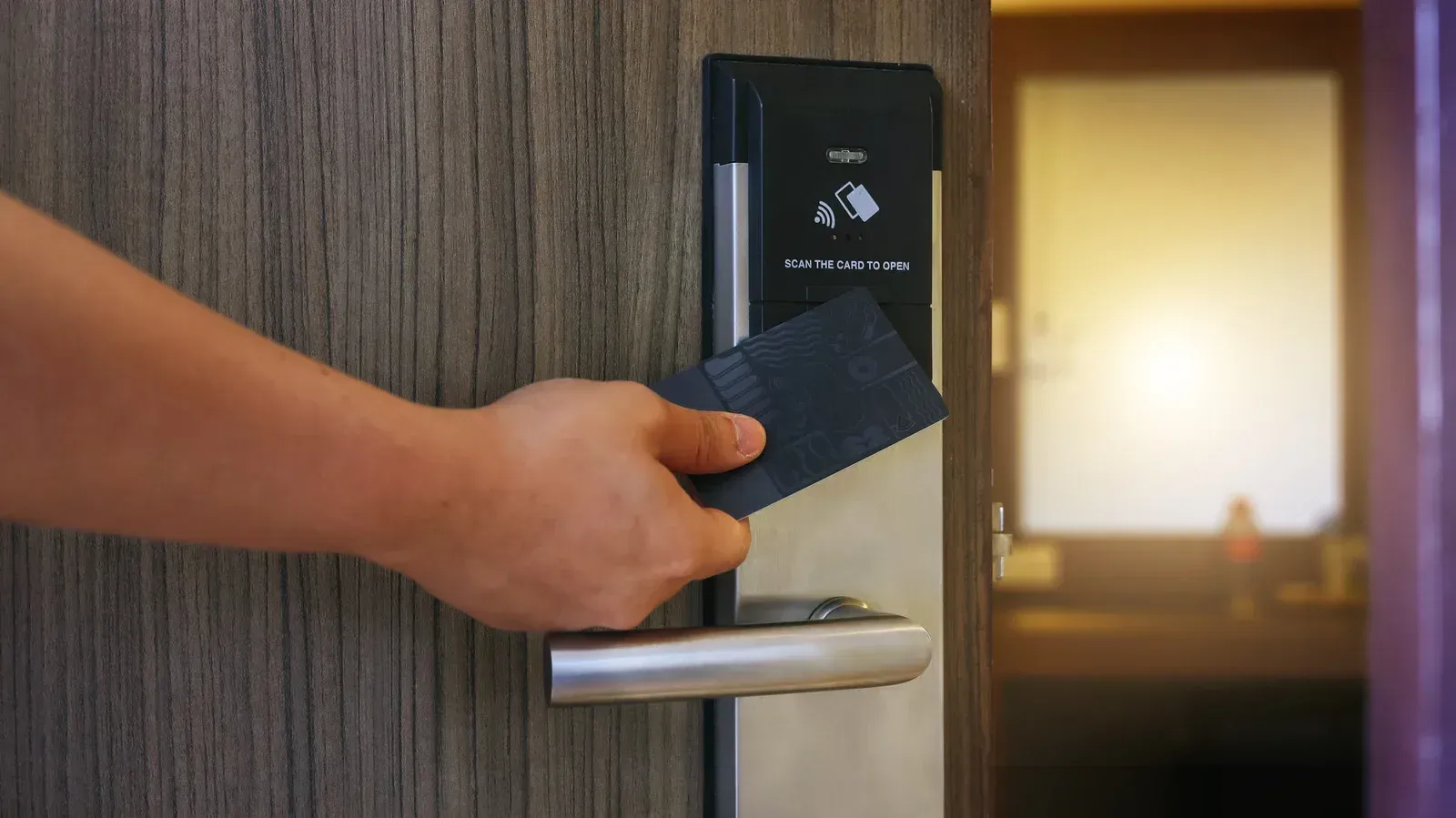 A person is using a key card to open a hotel door.
