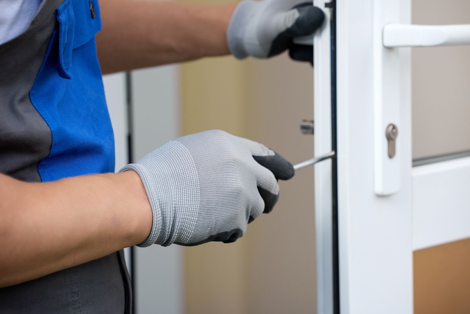 Gloved technician using a screwdriver to open a white door lock