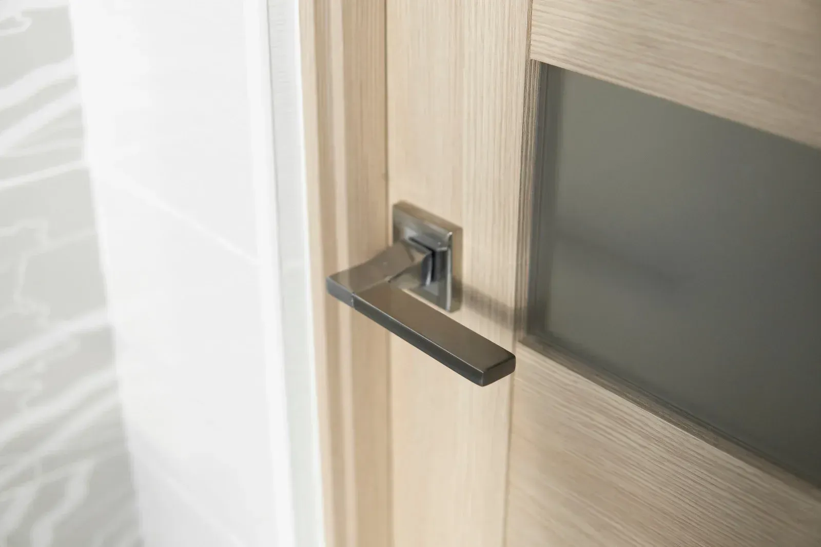 Modern wooden door with a silver handle and frosted glass panel