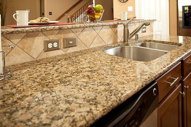A modern kitchen counter features polished granite stone benchtops and a stainless steel sink.