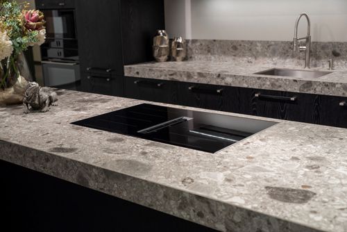 Black induction cooktop with built-in ventilation on sleek grey stone benchtops in a modern kitchen.