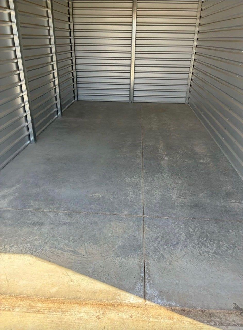 Cleanup King LLC - Empty gray storage unit, concrete floor, corrugated metal walls and door.