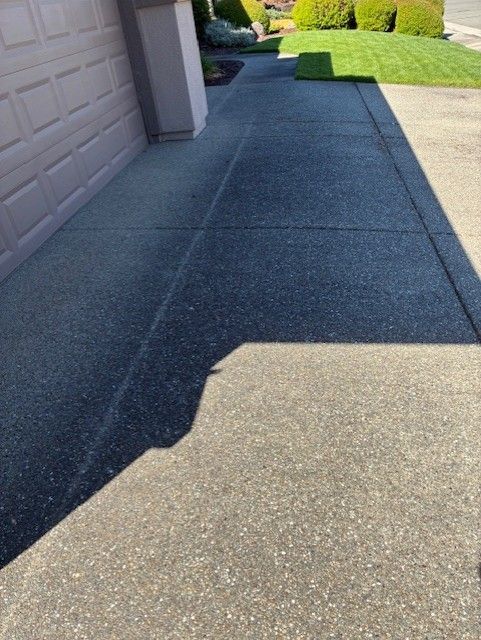 Cleanup King LLC - Sidewalk with a rough, speckled surface next to a garage and a grassy area.