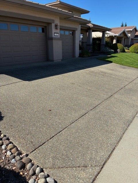 Cleanup King LLC - Driveway leading to a house with a garage, bordered by a sidewalk and rocks. Sunny day.
