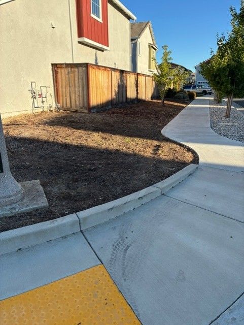 Cleanup King LLC - Residential property with a brown fence, freshly tilled soil, and a sidewalk.