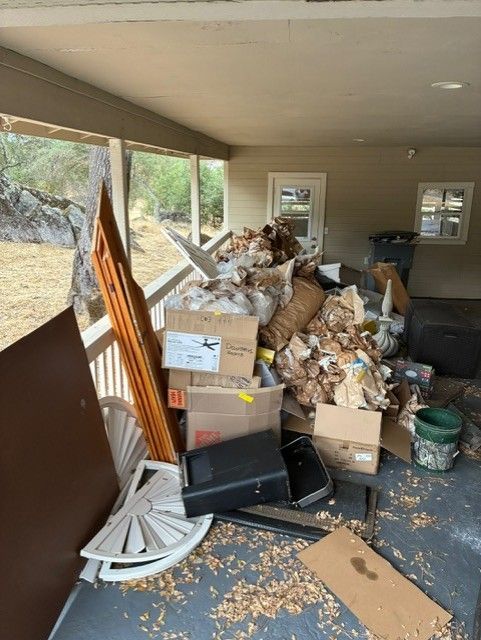 Cleanup King LLC - Porch cluttered with large pile of trash, cardboard boxes, and miscellaneous items.