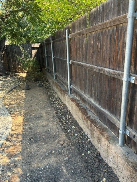 Cleanup King LLC - Dirt path beside a weathered wooden fence with metal posts in an outdoor setting.