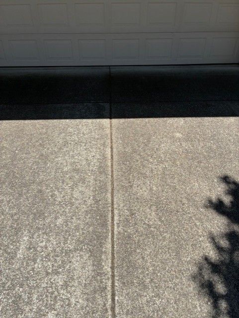 Cleanup King LLC - Concrete driveway with a dark line dividing it, below a white garage door.